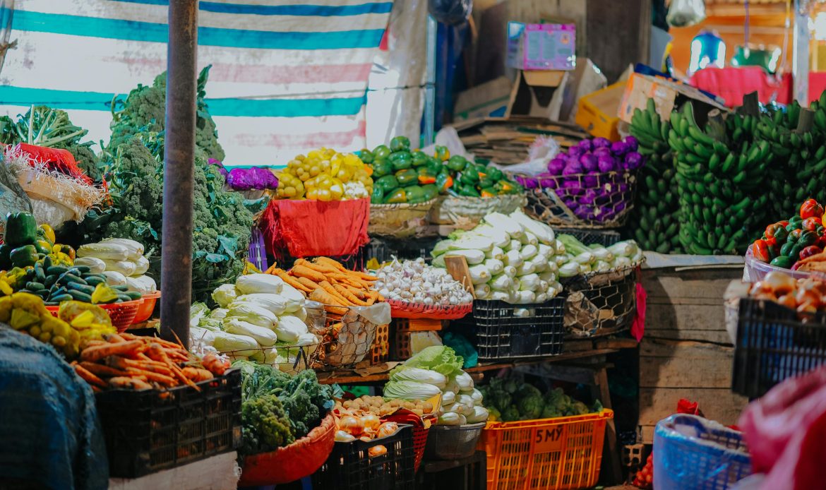 Vibrant array of fresh fruits and vegetables displayed at a bustling market stall.